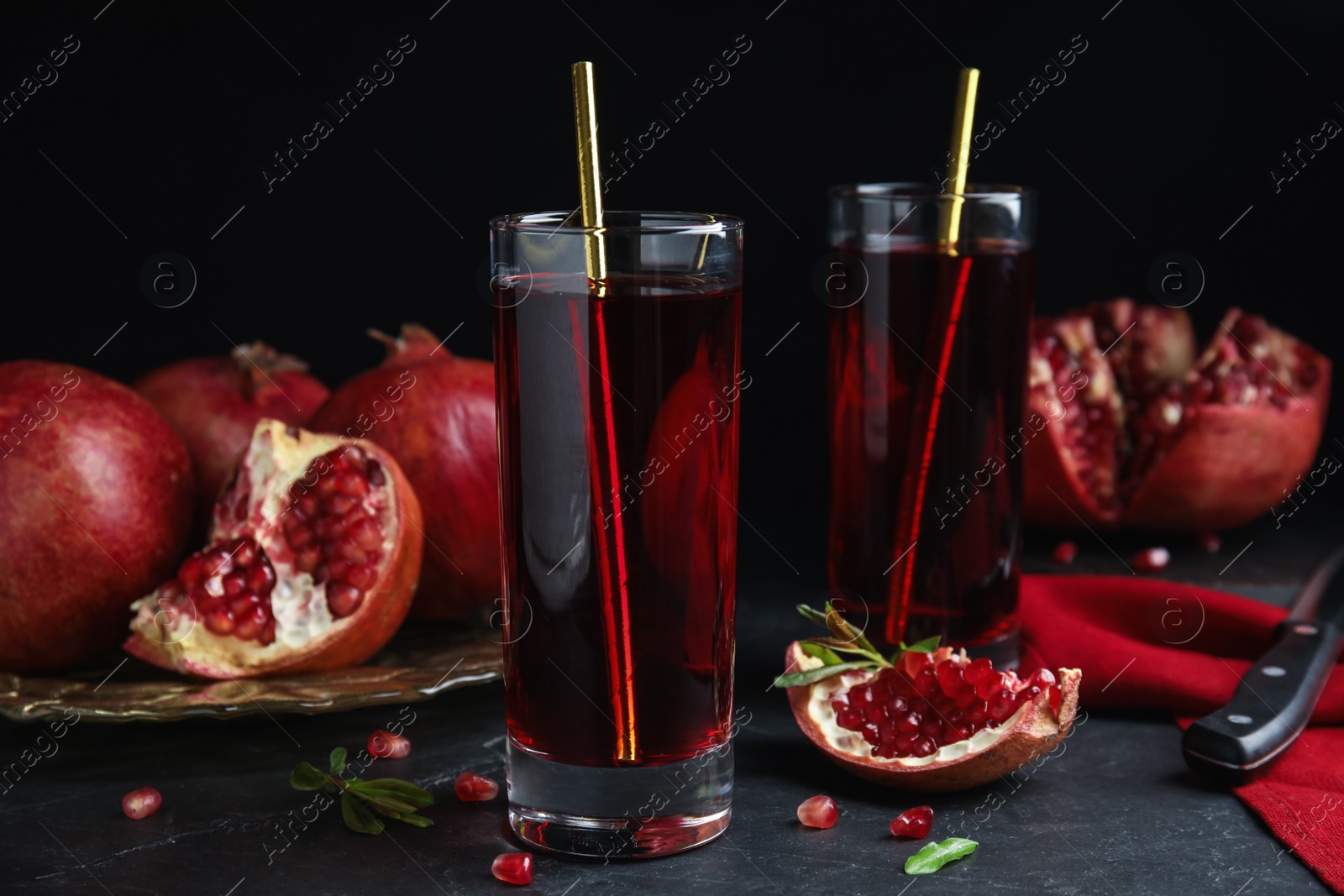 Photo of Pomegranate juice and fresh fruits on black table