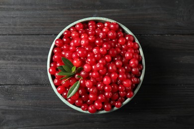 Photo of Tasty ripe cranberries on black wooden table, top view