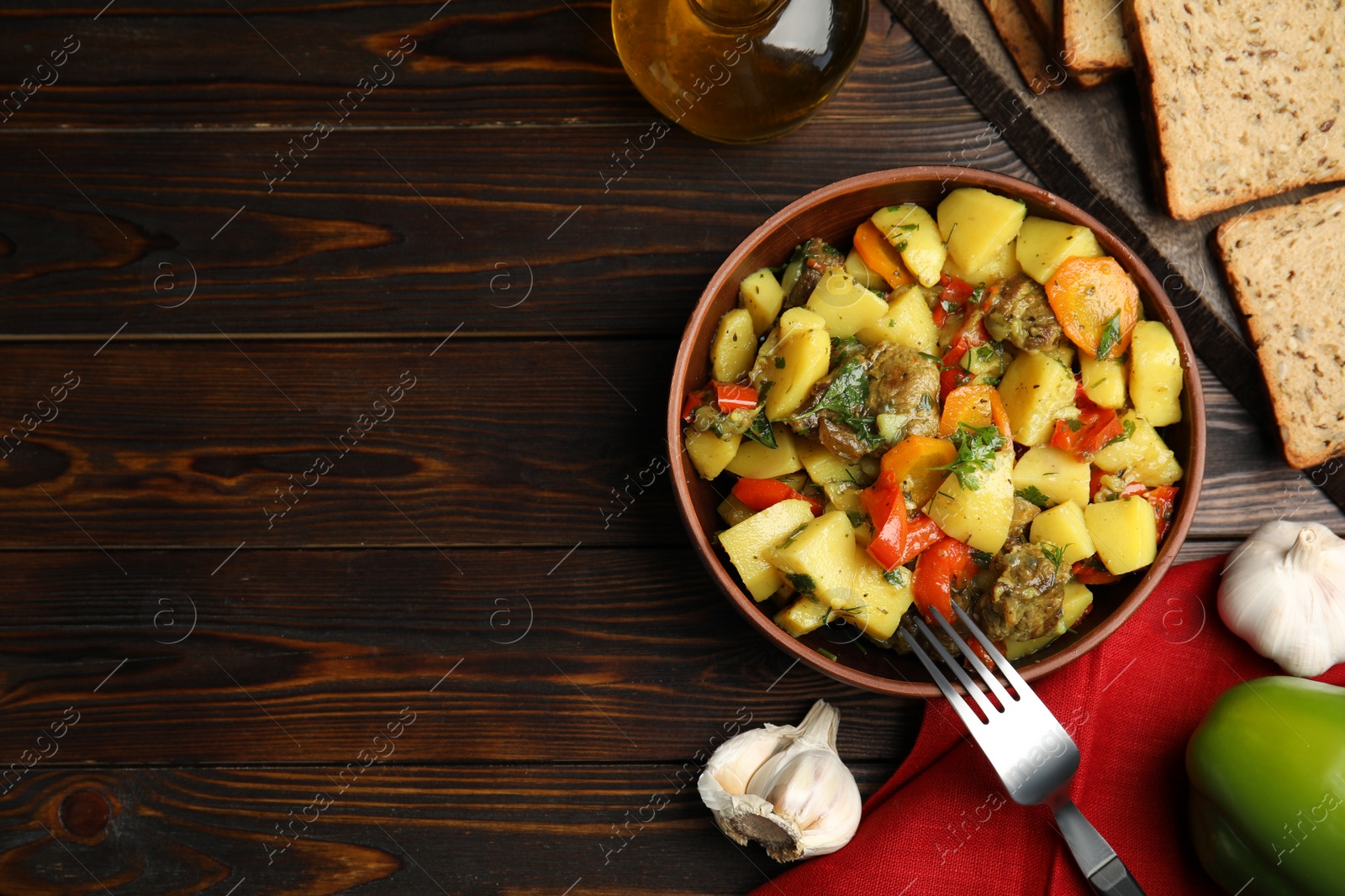 Photo of Tasty cooked dish with potatoes in earthenware served on wooden table, flat lay. Space for text