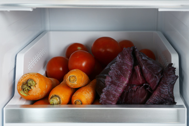 Photo of Open refrigerator full of fresh vegetables, closeup