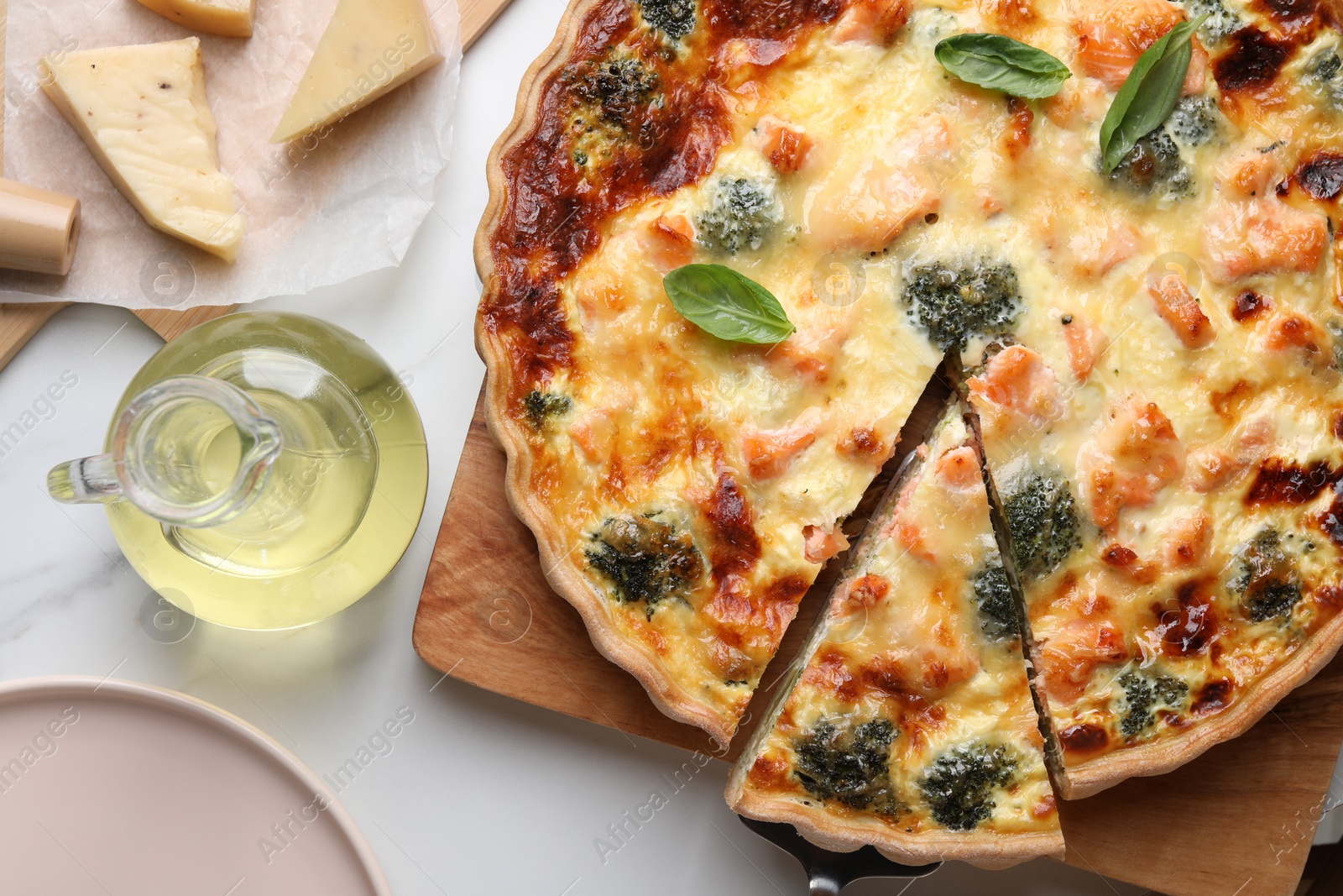 Photo of Delicious homemade quiche and ingredients on white table, flat lay