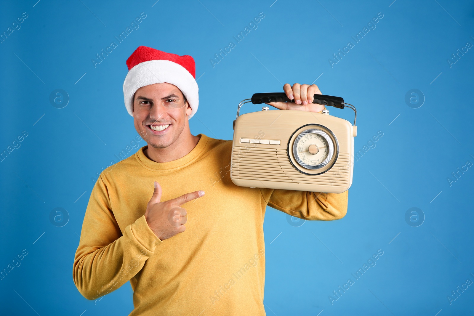 Photo of Happy man with vintage radio on blue background. Christmas music