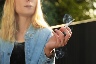 Young woman smoking cigarette outdoors, closeup view