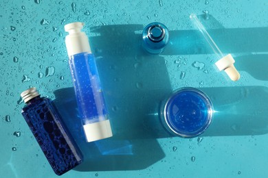 Set of cosmetic products on wet turquoise background, top view