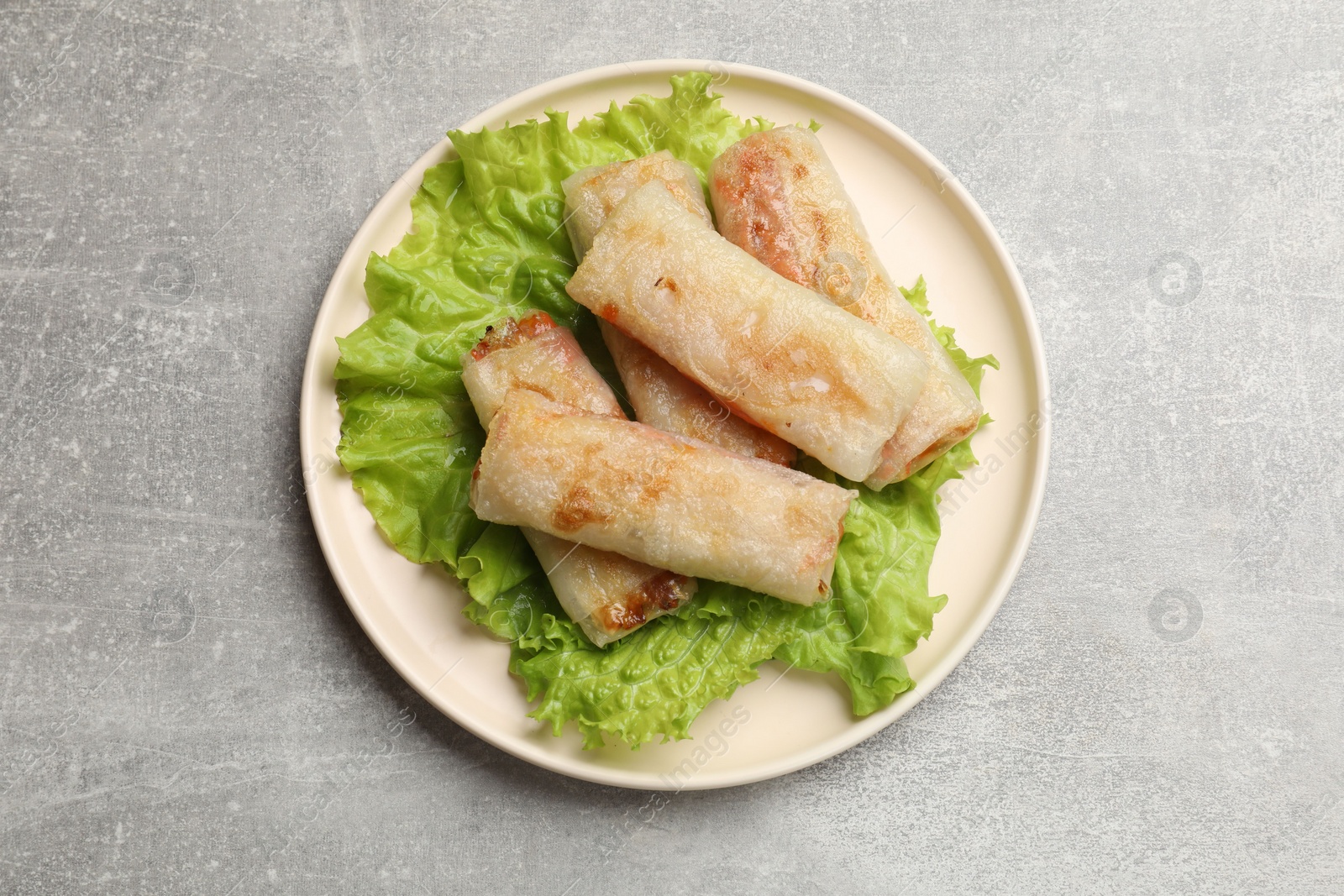 Photo of Delicious fried spring rolls on grey table, top view