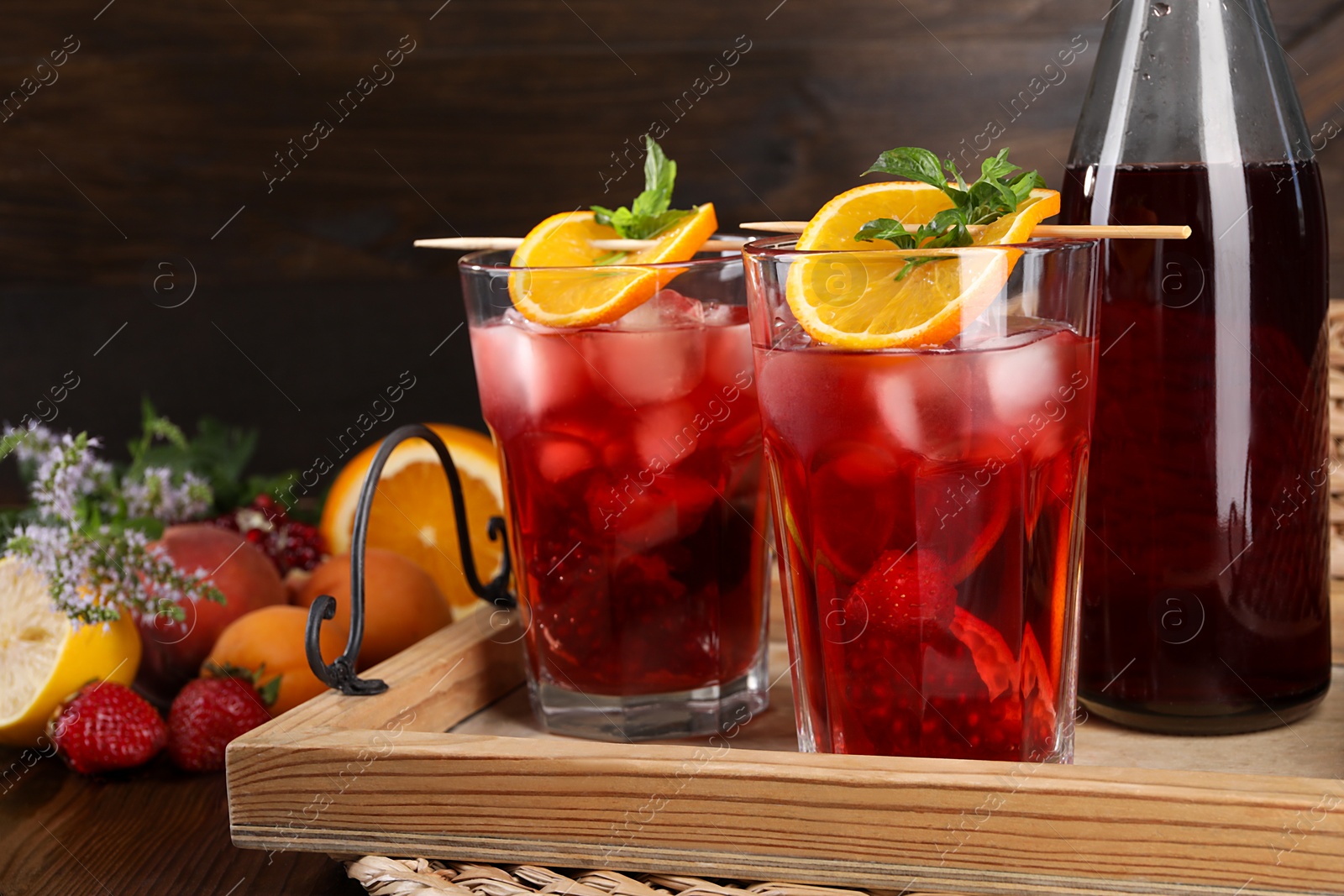 Photo of Bottle and glasses of delicious refreshing sangria on wooden table