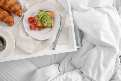 Photo of Good morning. Tray with tasty breakfast on bed, top view