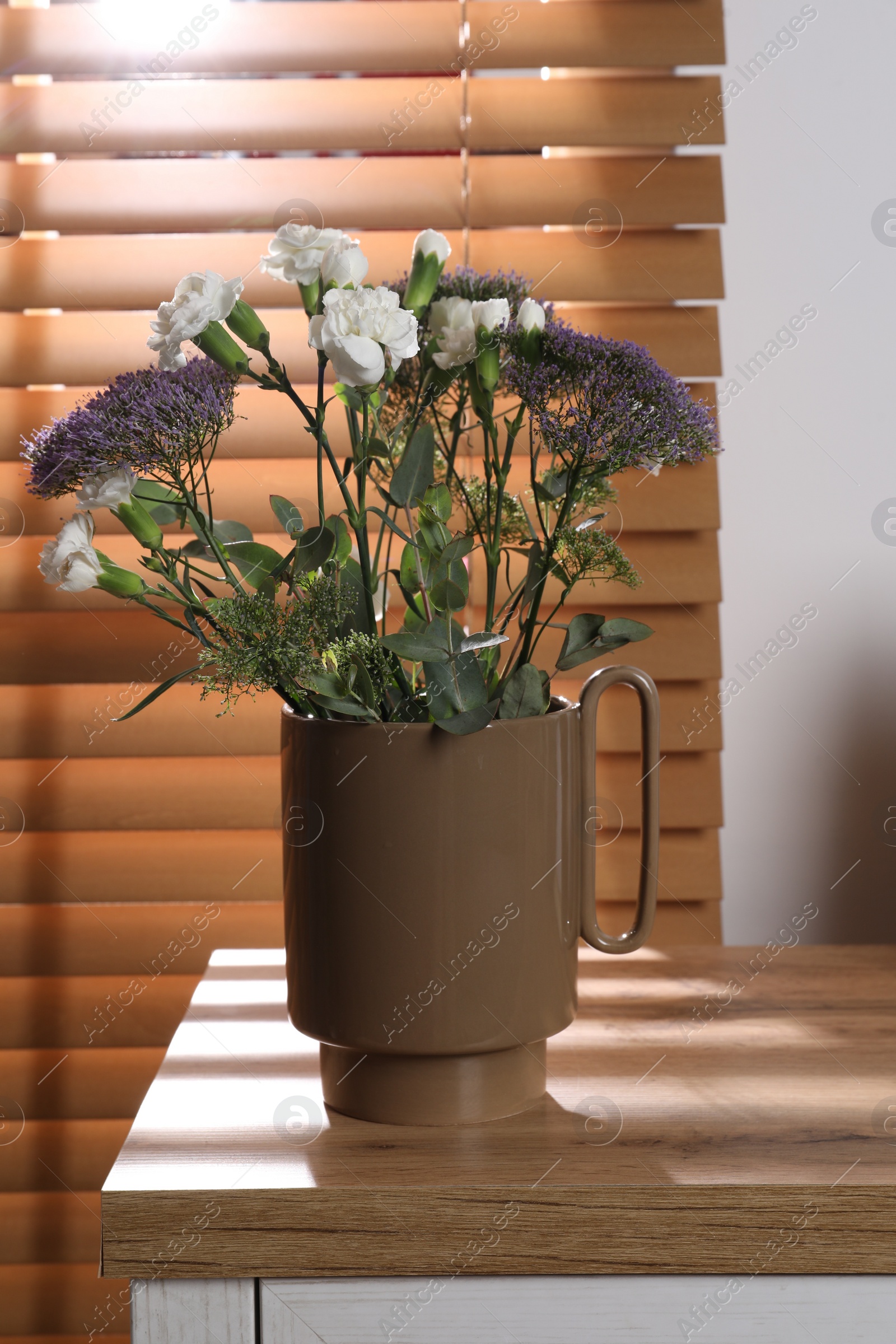 Photo of Stylish ceramic vase with beautiful flowers and eucalyptus branches on wooden table near window