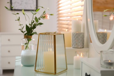 Photo of Burning scented candles and bouquet on dressing table indoors