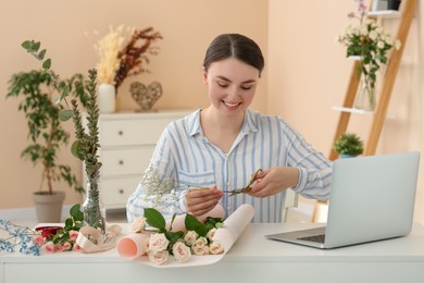 Photo of Woman making bouquet following online florist course at home. Time for hobby