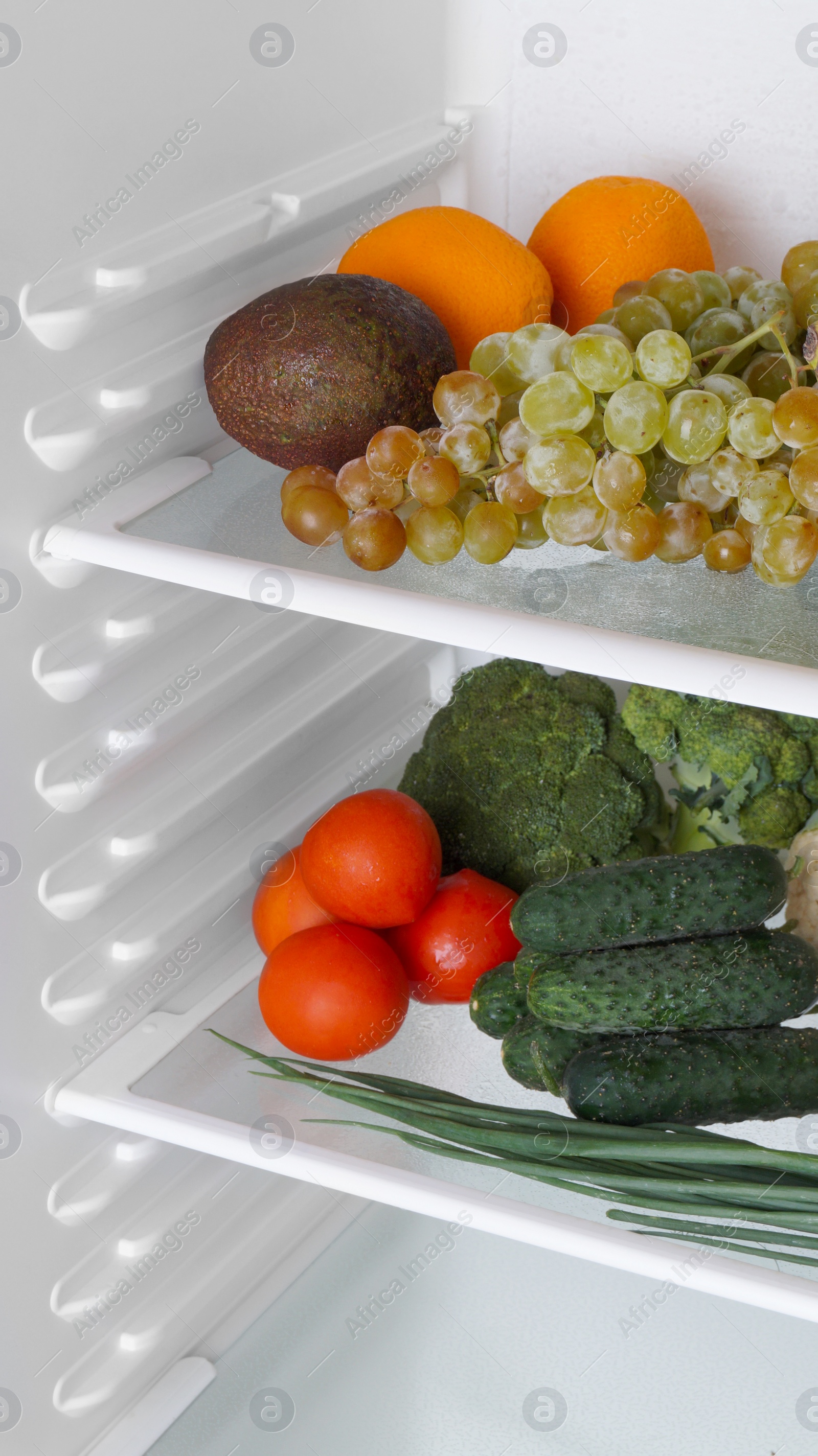 Photo of Open refrigerator with many different fresh vegetables and fruits