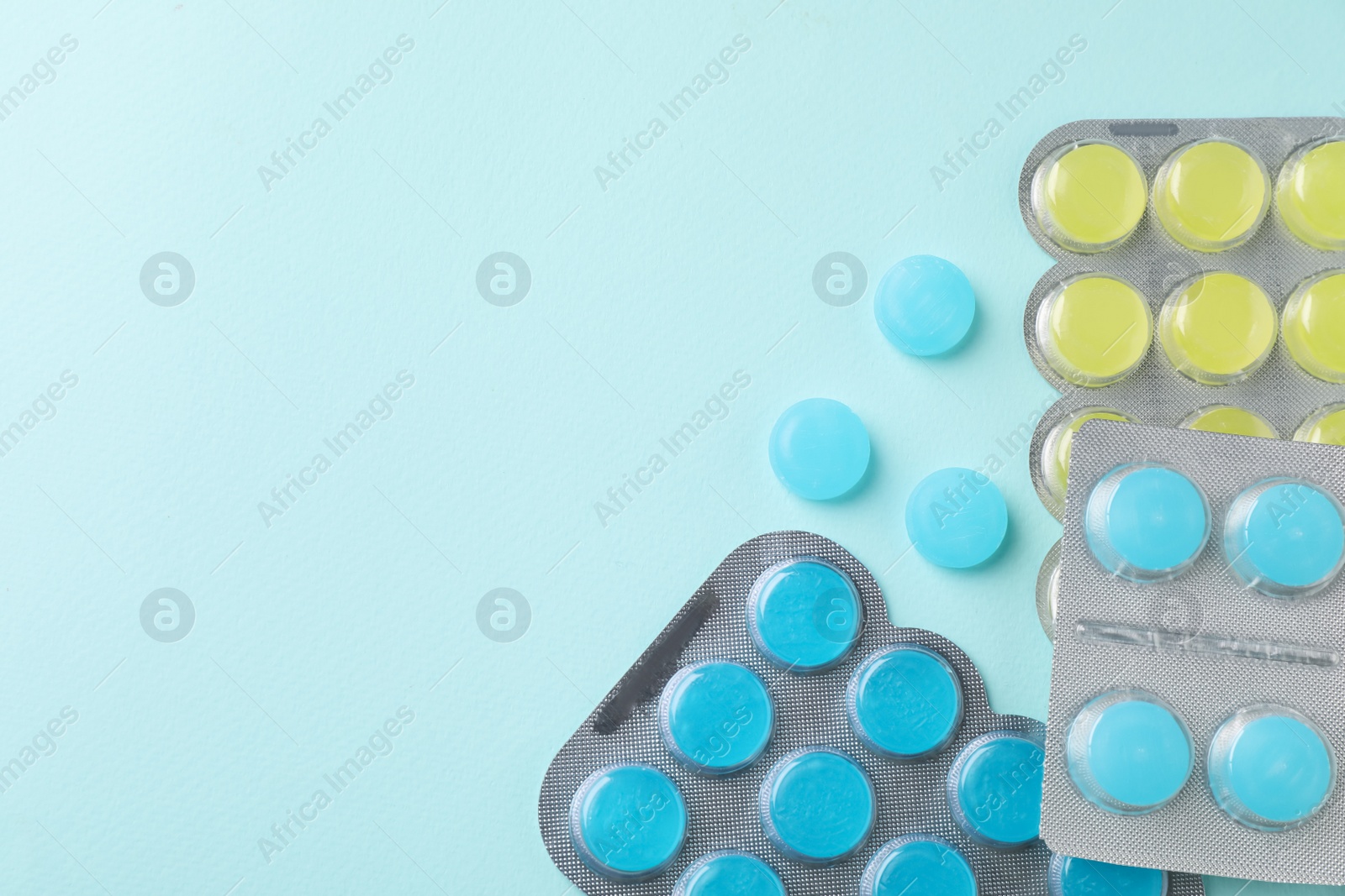 Photo of Colorful cough drops on light blue background, flat lay. Space for text