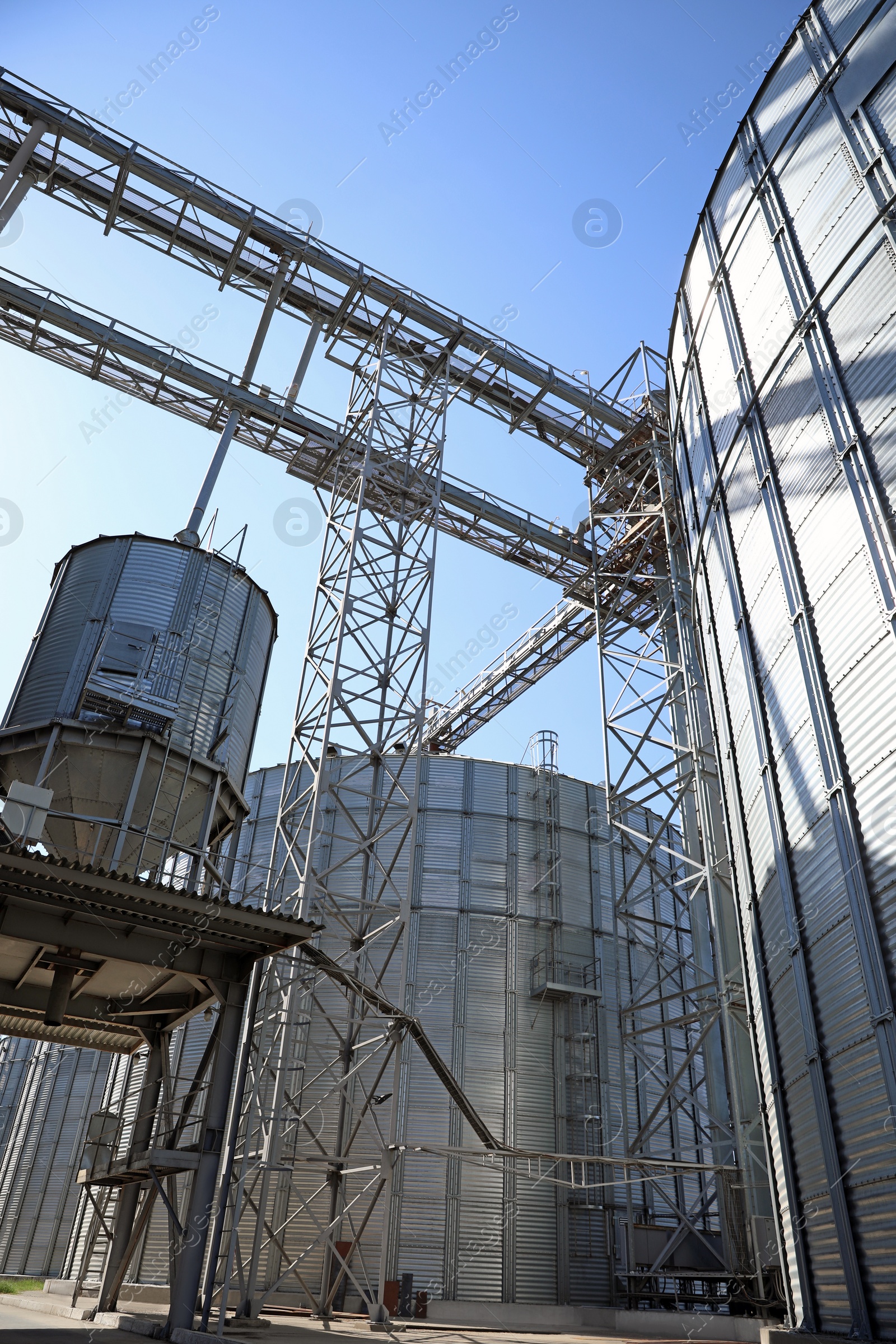 Photo of Modern granaries for storing cereal grains against blue sky, low angle view