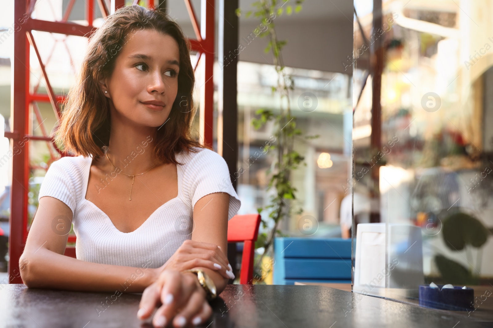 Photo of Portrait of beautiful young woman in outdoor cafe. Space for text