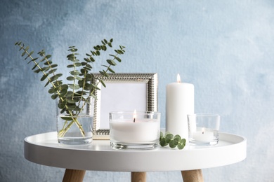 Photo of Composition with burning aromatic candles on table near color wall