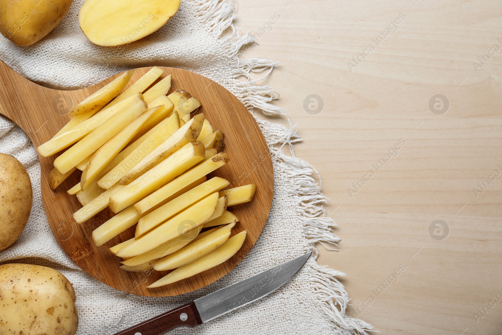 Photo of Cut and whole raw potatoes on white wooden table, flat lay. Space for text