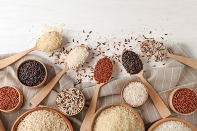 Photo of Flat lay composition with brown and other types of rice on wooden background