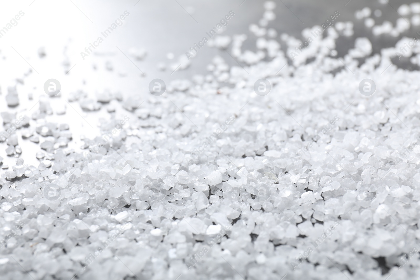 Photo of Scattered white natural salt on table, closeup