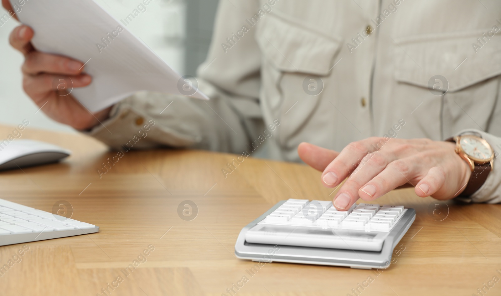 Photo of Professional accountant using calculator at wooden desk in office, closeup