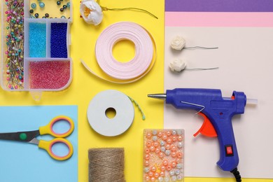 Photo of Flat lay composition with hot glue gun and handicraft materials on color background