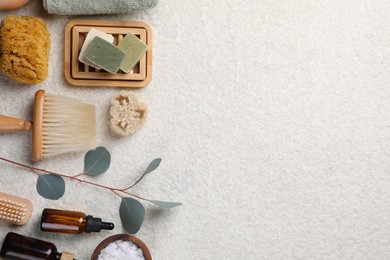 Flat lay composition with different spa products and eucalyptus branch on light grey textured table. Space for text