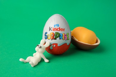Photo of Slynchev Bryag, Bulgaria - May 25, 2023: Kinder Surprise Eggs, plastic capsule and toy bunny on green background