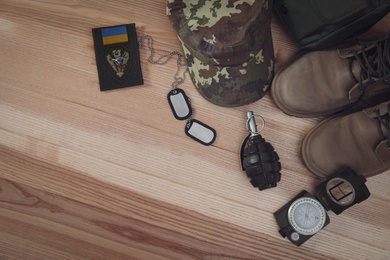 Photo of MYKOLAIV, UKRAINE - SEPTEMBER 26, 2020: Tactical gear and Ukrainian army patch on table, flat lay. Space for text