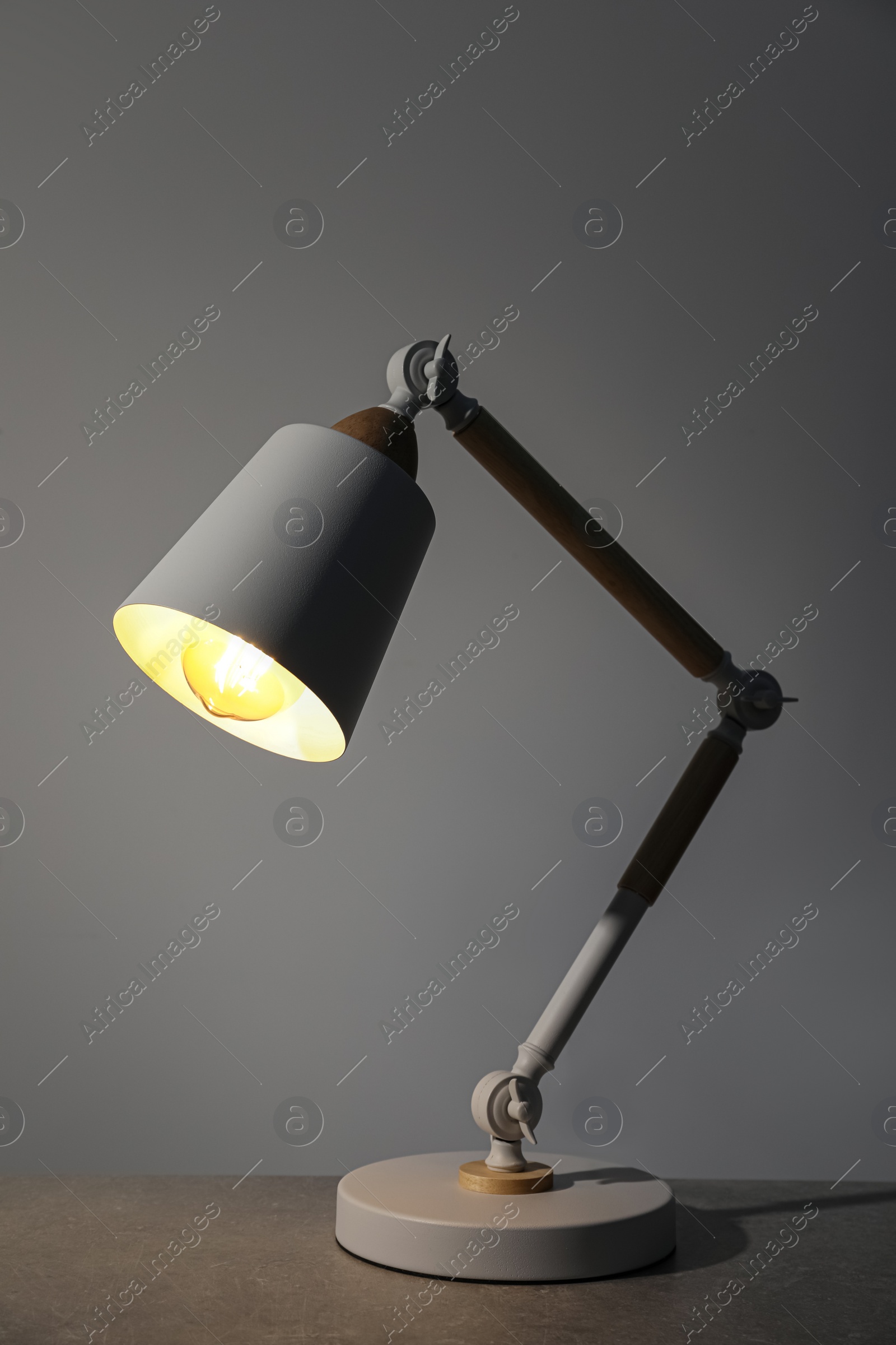 Stylish modern desk lamp on light gray table Photo of Stylish modern desk lamp on light gray table