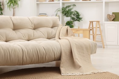 Photo of Comfortable sofa with beige blanket in living room