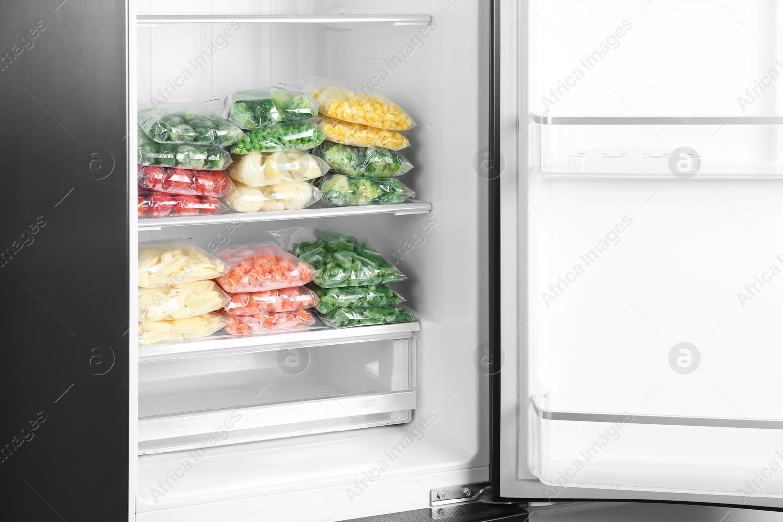 Photo of Plastic bags with different frozen vegetables in refrigerator