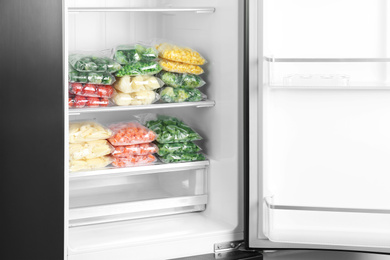 Photo of Plastic bags with different frozen vegetables in refrigerator