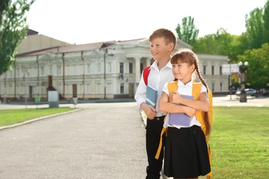 Photo of Children with school stationery standing on city street