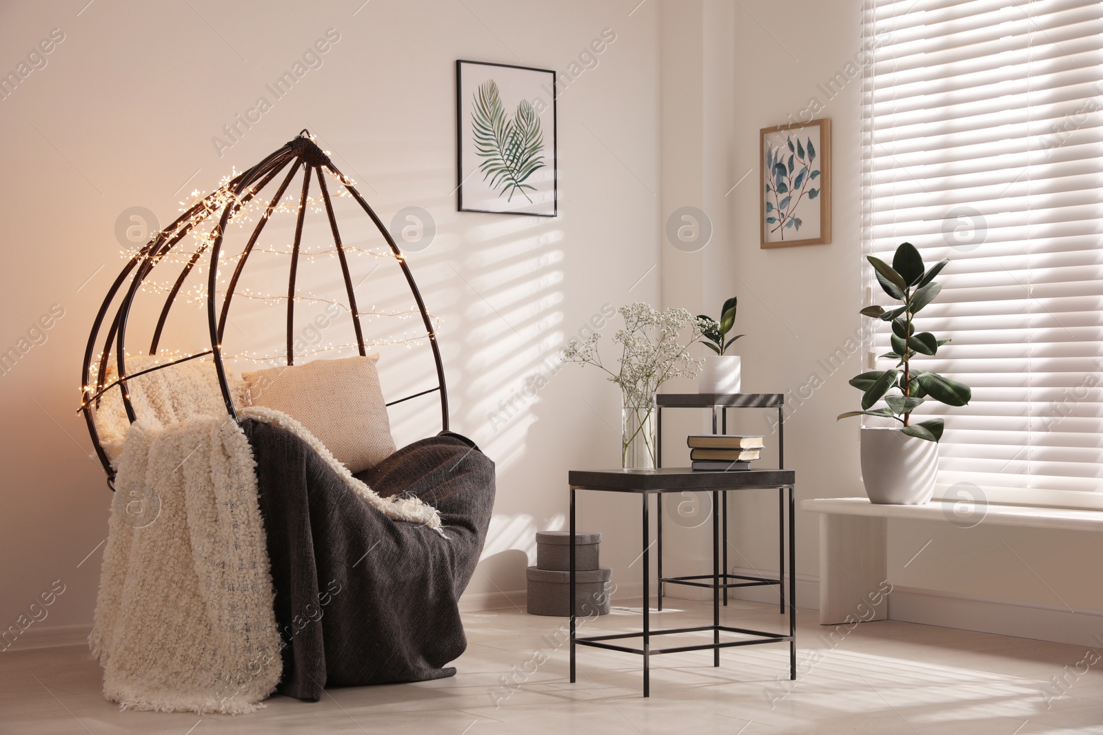 Photo of Cozy hanging chair with fairy lights in modern living room. Interior design