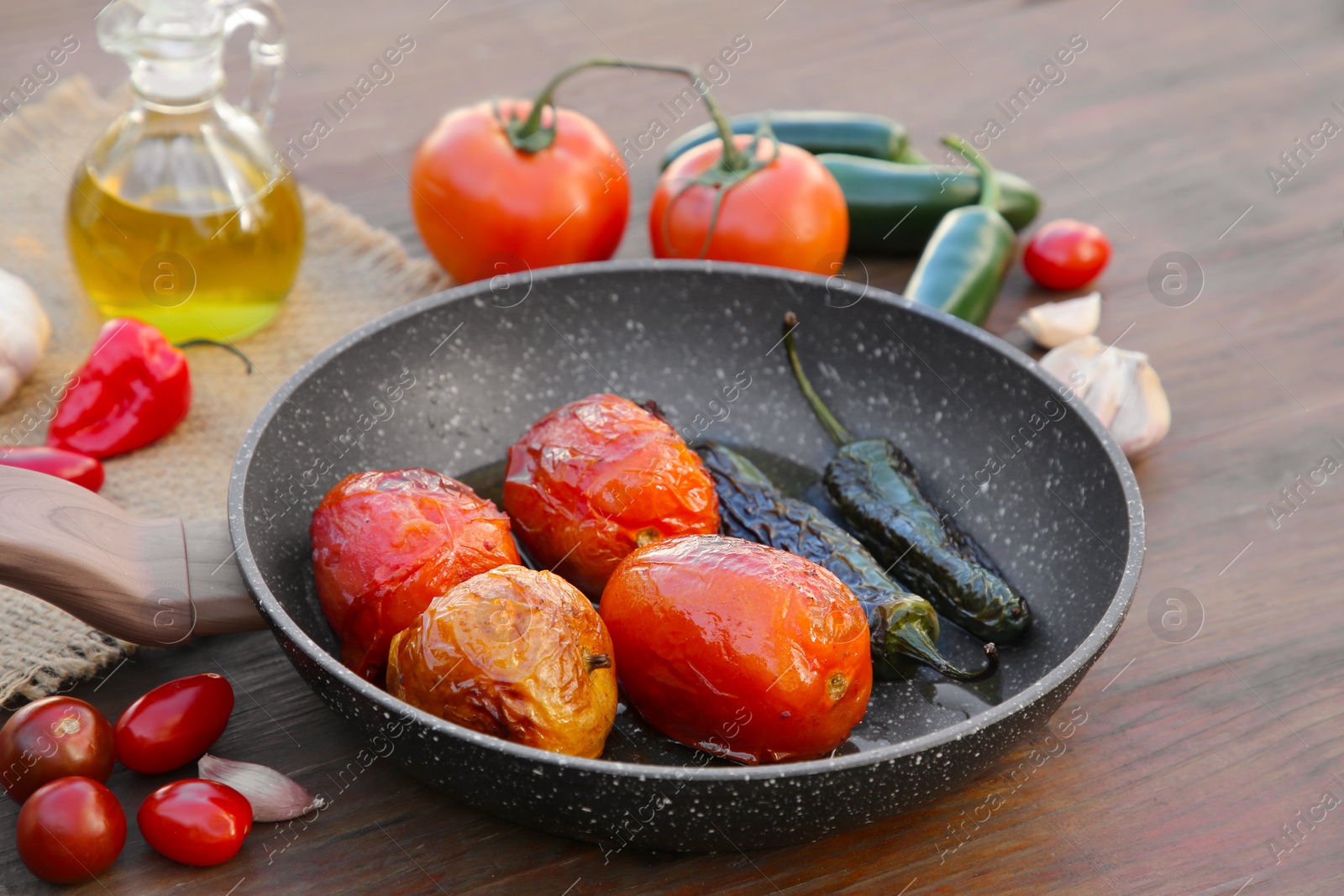 Photo of Frying pan and ingredients for salsa sauce on wooden table