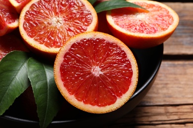 Photo of Slices of fresh ripe red orange on wooden table, closeup