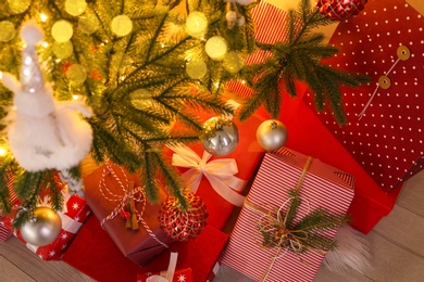 Photo of Pile of gift boxes near Christmas tree on floor, above view
