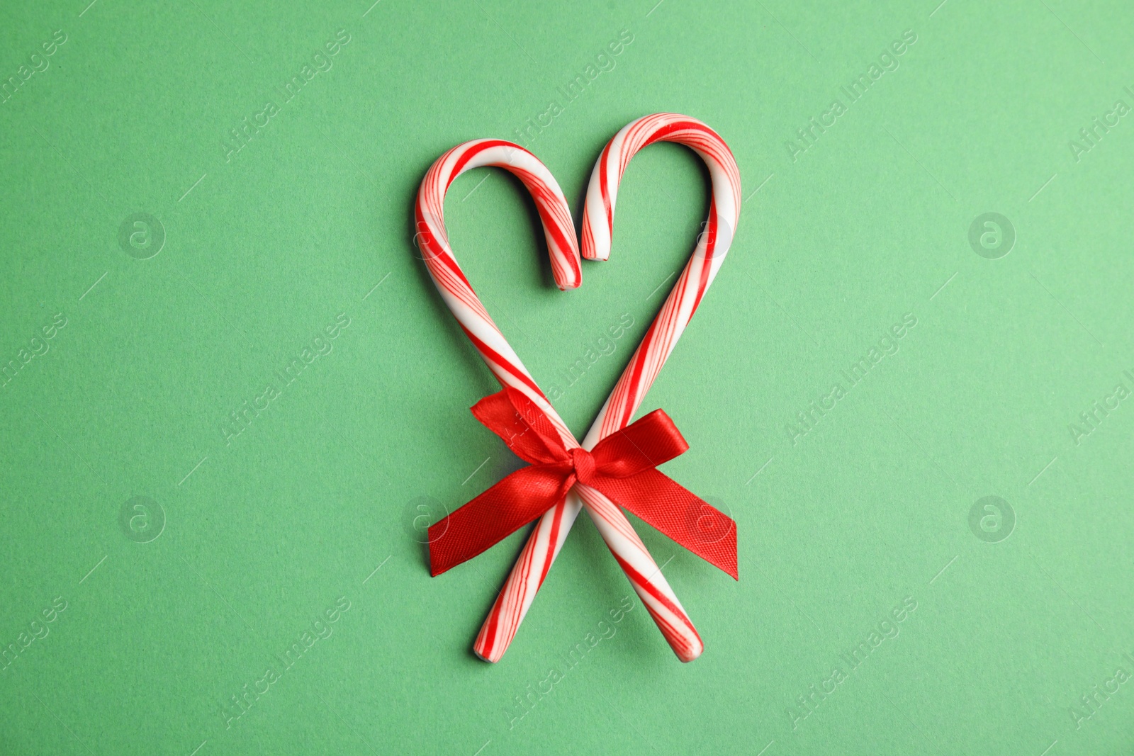 Photo of Candy canes on green background, flat lay