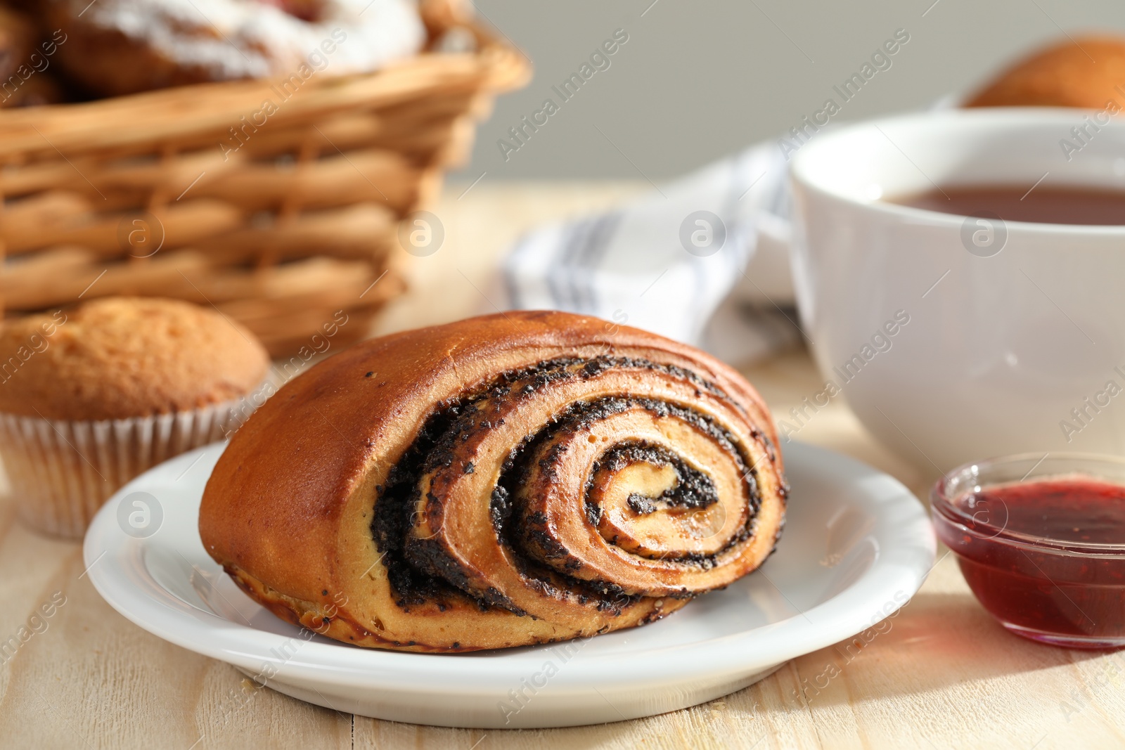 Photo of Tasty bun with poppy seeds on wooden table, closeup