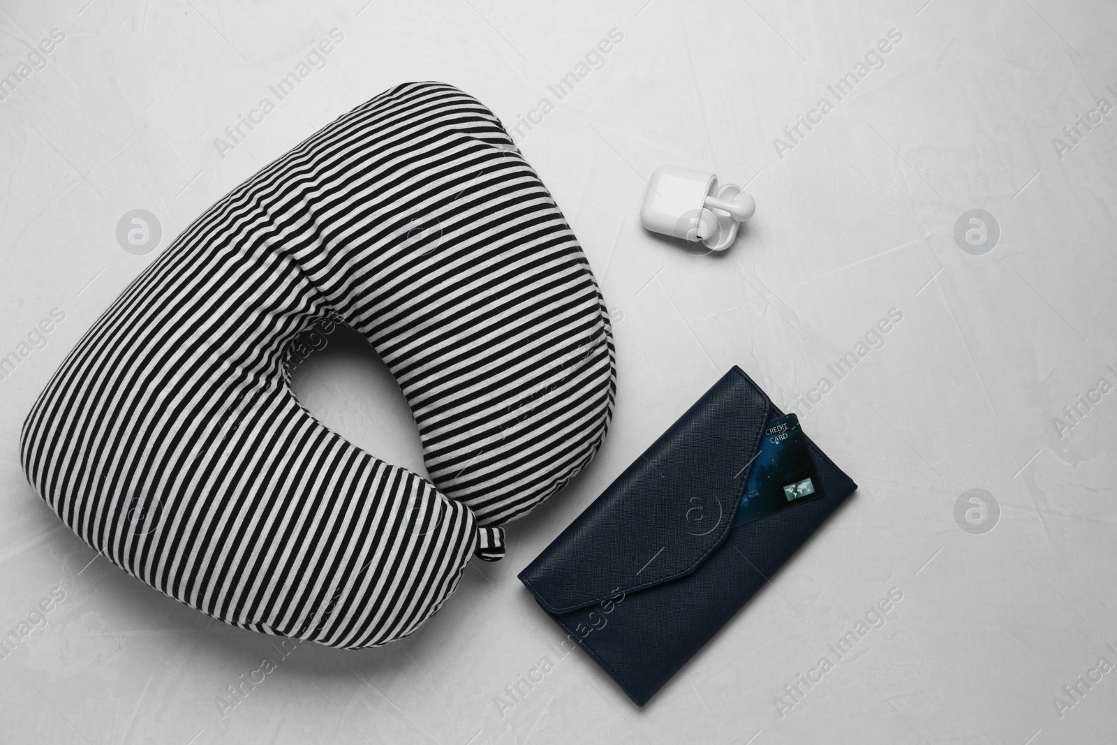 Photo of Striped travel pillow, wallet with credit card and earphones on gray background, flat lay