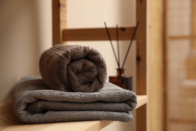 Photo of Soft towels on wooden shelf indoors, closeup