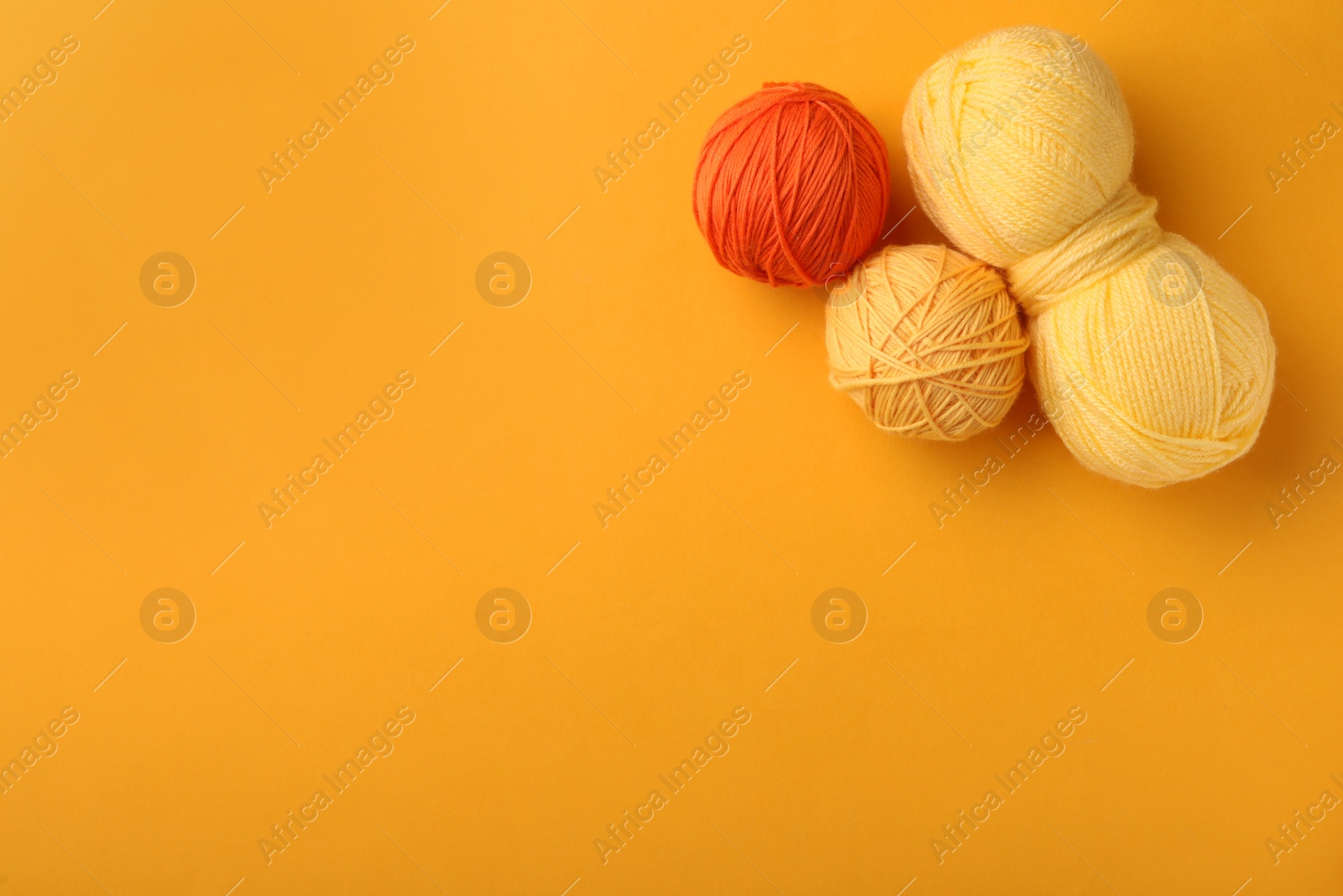 Photo of Soft colorful woolen yarns on yellow background, flat lay. Space for text