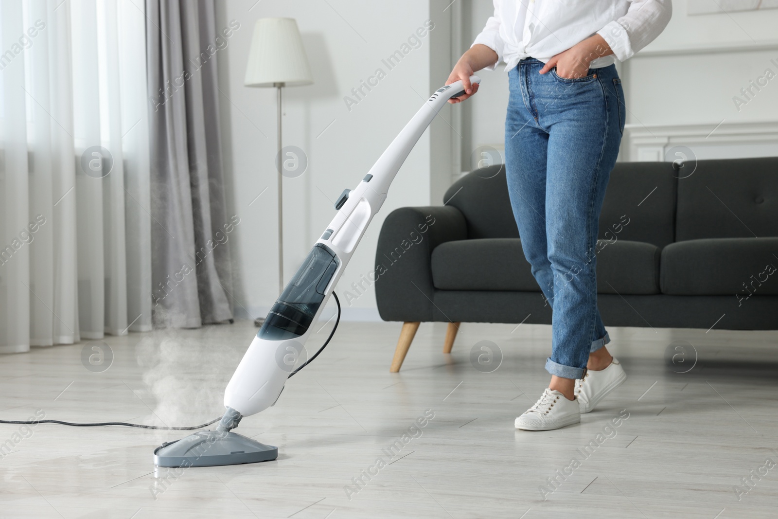 Photo of Woman cleaning floor with steam mop at home, closeup