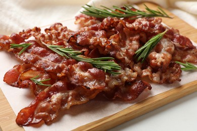 Photo of Slices of tasty fried bacon with rosemary on white table, closeup