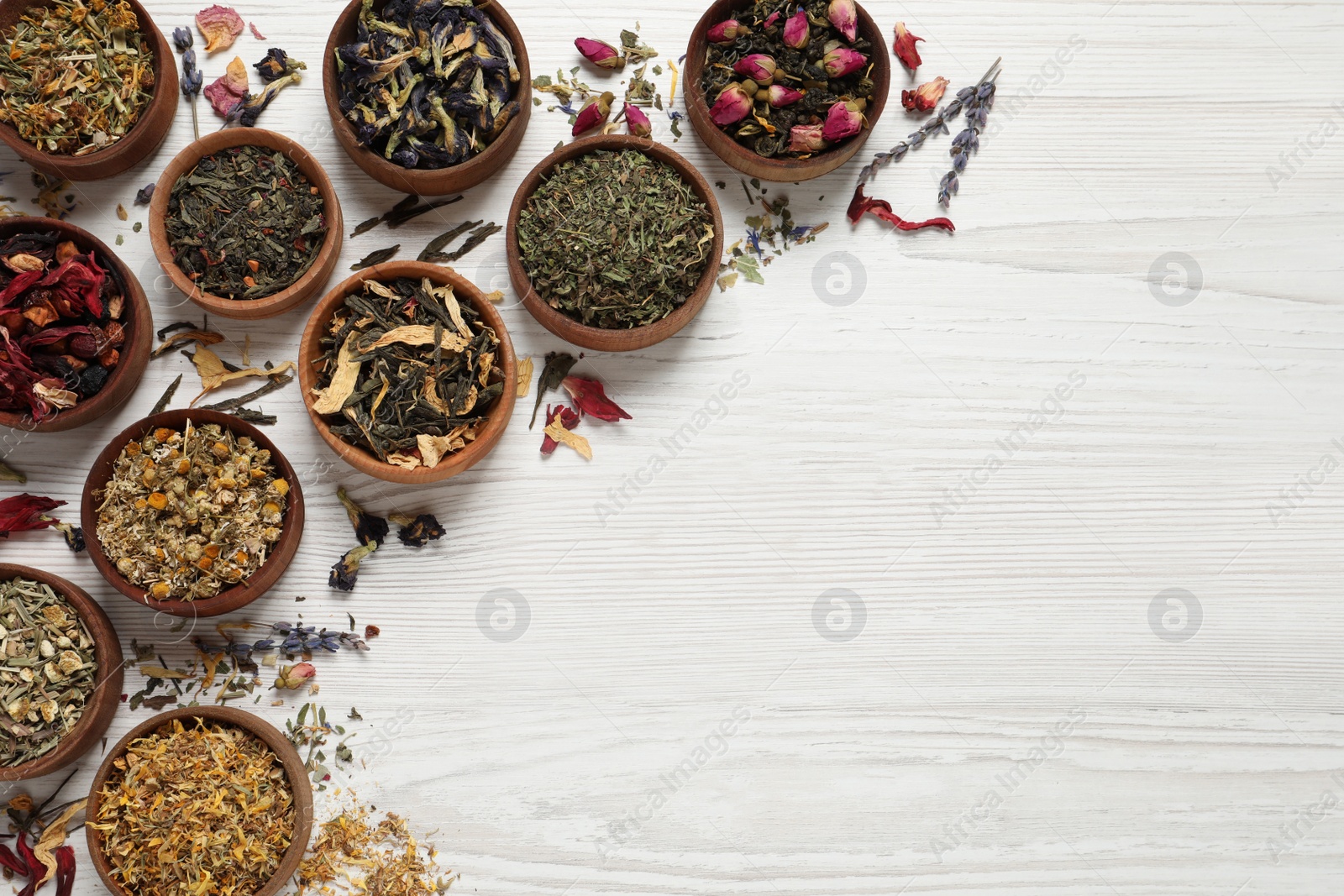 Photo of Flat lay composition with different dry teas on white wooden table. Space for text
