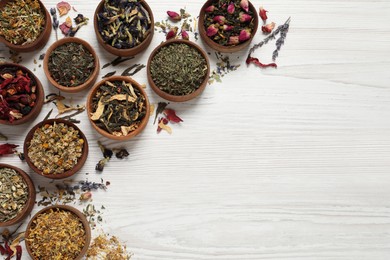 Flat lay composition with different dry teas on white wooden table. Space for text