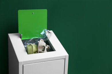 Photo of Overfilled trash bin on color background, space for text. Recycling concept