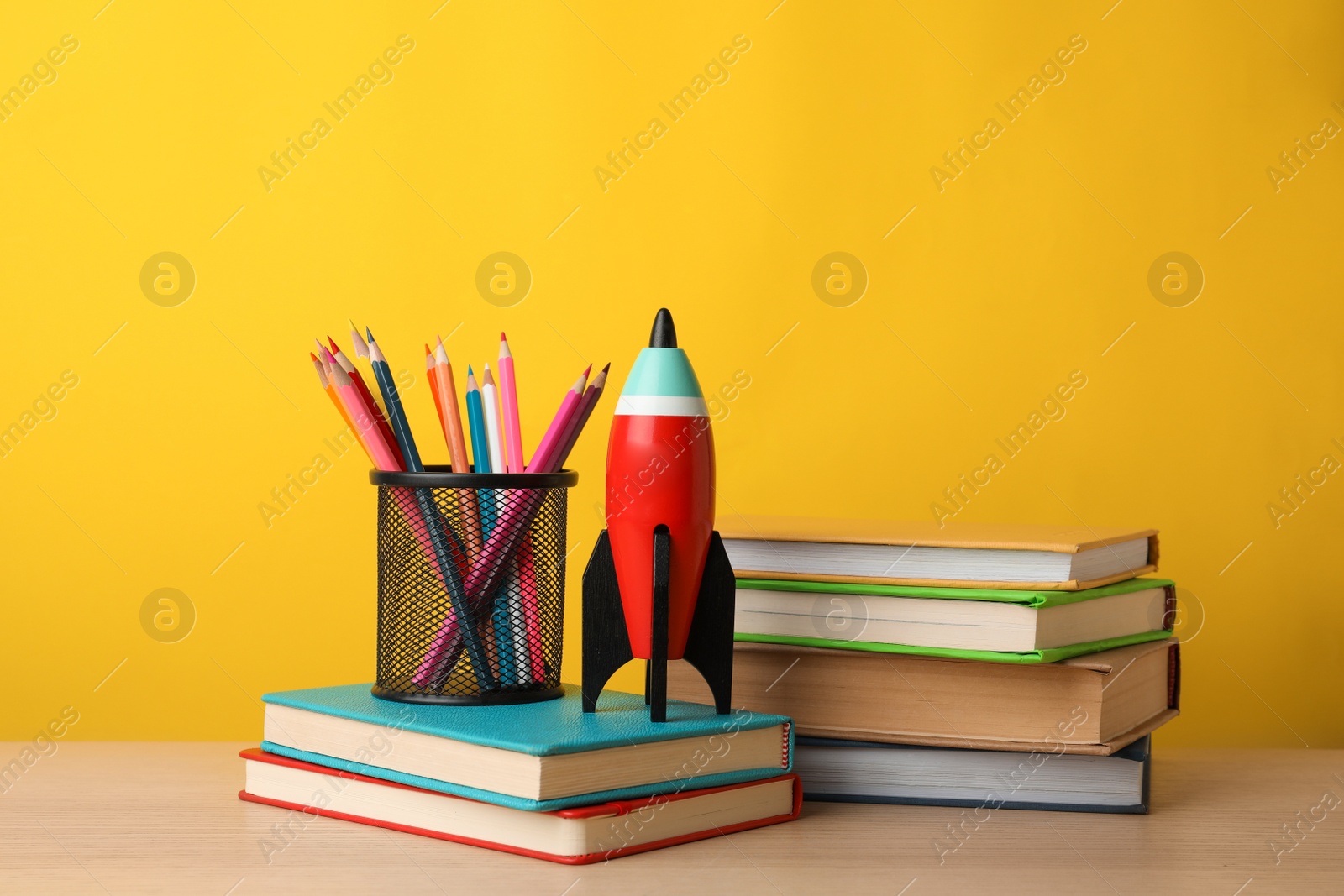 Photo of Bright toy rocket and school supplies on wooden table