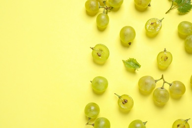 Flat lay composition with fresh ripe juicy grapes on yellow background, space for text