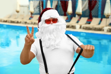 Authentic Santa Claus wearing sunglasses near pool at resort