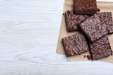 Photo of Delicious chocolate brownies on white wooden table, top view. Space for text